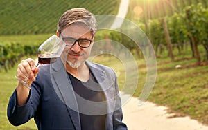 Portrait of happy man in vineyard with glass of wine