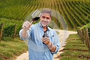 Portrait of happy man in vineyard with glass of wine