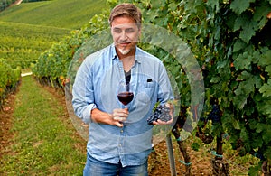 Portrait of happy man in vineyard with glass of wine