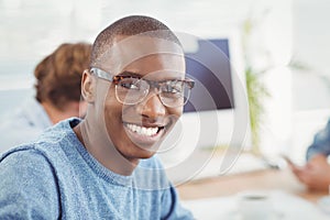 Portrait of happy man wearing eyeglasses while sitting at desk