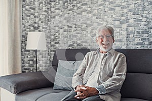 Portrait of happy mature 80s man sit on couch at home look at camera posing relaxing on weekend, smiling positive senior 70s