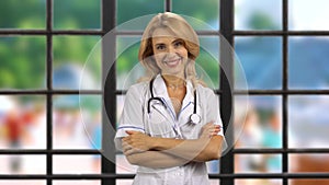 Portrait of happy mature blonde female doctor puts on stethoscope on her neck.