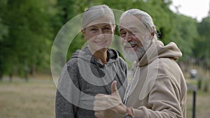 Portrait of the happy mature couple standing together in the park. Elderly family before the sport training. Aging