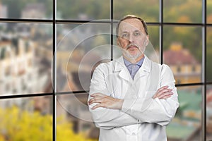 Portrait Of Happy Mature Male Doctor With Folded Arms.