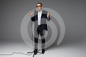 Portrait of a happy mature man presented with microphone or singing isolated full body on white background with copy space