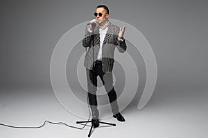 Portrait of a happy mature man presented with microphone or singing isolated full body on white background with copy space