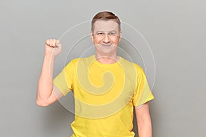 Portrait of happy mature man raising clenched fist up and smiling