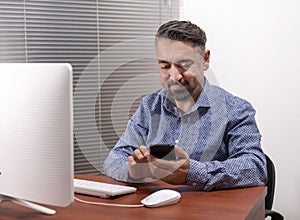 Portrait Of A Happy Mature Man Using Desktop Computer And Smart Phone