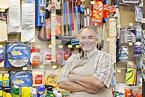 Portrait of a happy mature salesperson with arms crossed in hardware store