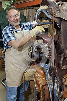 Portrait of a happy mature salesperson standing by horse riding tack in feed store