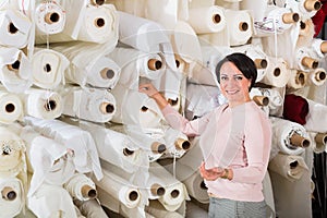 Portrait of happy mature woman with cloth rolls