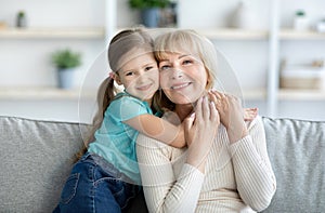 Portrait of happy mature woman and granddaughter hugging and posing