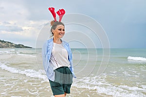 Portrait of happy mature woman in holiday ears on beach