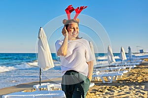 Portrait of happy mature woman in holiday ears on the beach