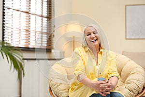 Portrait of happy mature woman sitting in papasan chair