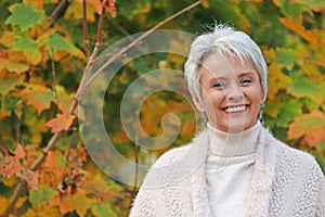 Portrait of a happy mature woman with warm pullover in nature