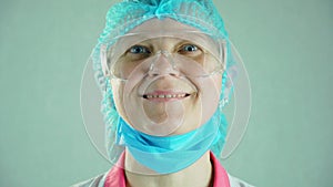 Portrait of happy medical nurse in protective glasses take off face mask and smiling during coronavirus pandemic