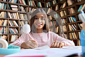 Portrait of happy Mexican teen student girl sitting at table camera looking.