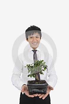 Portrait of happy mid adult businessman holding potted plant over white background