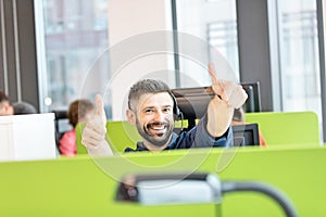 Portrait of happy mid adult businessman wearing headset while gesturing thumbs up in office