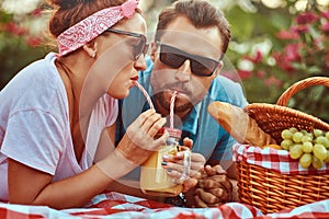 Portrait of a happy middle age couple during romantic dating outdoors, enjoying a picnic while lying on a blanket in the