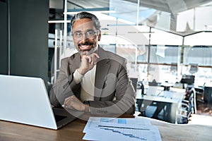 Portrait of happy middle aged business man looking at camera at work desk.