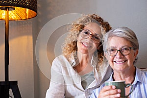 Portrait of happy middle-aged woman and senior mother spending time together at home