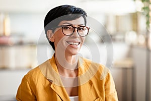 Portrait of happy middle aged woman smiling at camera indoors