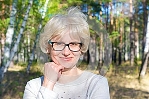 Portrait of a happy middle-aged woman walking in the park. Bright sunny summer day. The concept of freedom and joy