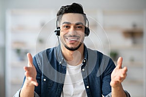Portrait of happy middle-eastern guy with headset having conversation