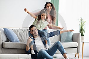 Portrait Of Happy Middle Eastern Parents Bonding With Their Child At Home