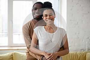 Portrait of happy millennial african couple hugging in new apartment photo