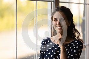 Portrait of happy millennial Latin 30s woman touching chin