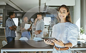 Portrait of a happy mixed race businesswoman working on a digital tablet in an office. Cheerful hispanic female