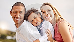 Portrait of a happy mixed race family spending time together on the beach. Adorable little girl enjoying vacation with