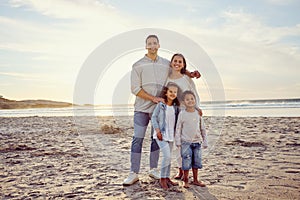 Portrait of a happy mixed race family standing together on the beach. Parents spending time with their cute son and