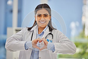 Portrait of a happy mixed race female doctor forming a heart shape with hands at a hospital. Caring gp smiling and
