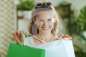 Portrait of happy modern woman shopper in sunglasses with bags