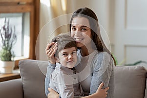 Portrait of happy mom and little son cuddle on couch