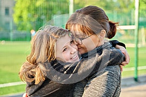 Portrait of happy mom and preteen daughter hugging together outdoor