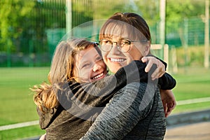 Portrait of happy mom and preteen daughter hugging together outdoor