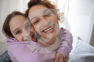 Portrait of happy mom and teen daughter hugging