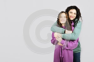 Portrait of happy mom and teen daughter spend time together. Teenage girl hugging her mother and having fun