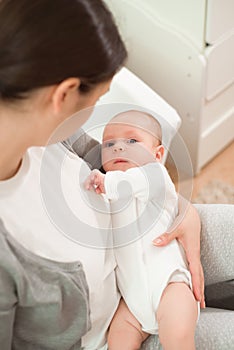 Portrait of happy mother and baby, parent and little kid relaxing at home. Family having fun together.