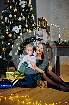 Portrait of a happy mother and a charming child celebrating Christmas. New year holiday. Baby with his mother in a festively