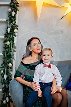 Portrait of a happy mother and a charming child celebrating Christmas. New year holiday. Baby with his mother in a festively