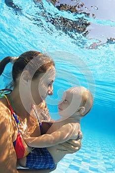 Portrait of happy mother with child swimming underwater in pool