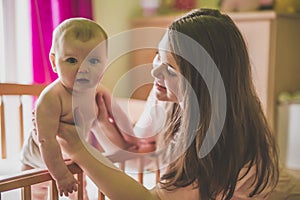 Portrait of a happy mother with cute baby in crib