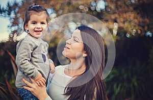 A portrait of a happy mother and daughter outdoors on a sunny day in the park.