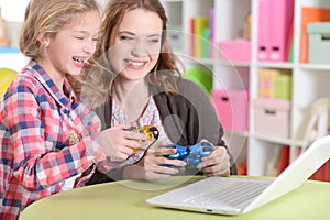 portrait of happy mother and daughter playing game on laptop